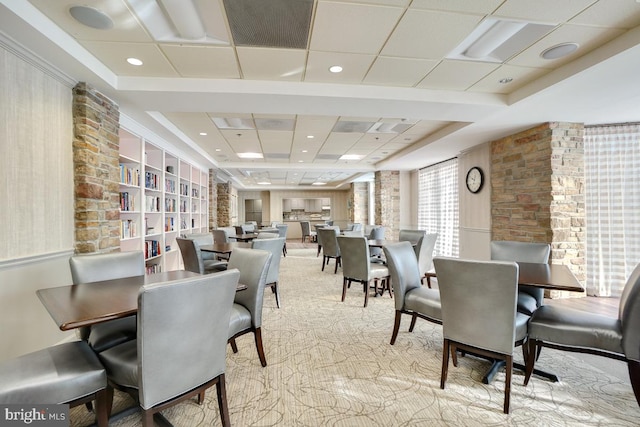 carpeted dining room with a paneled ceiling and built in features