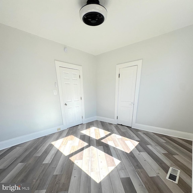 empty room featuring visible vents, baseboards, and wood finished floors