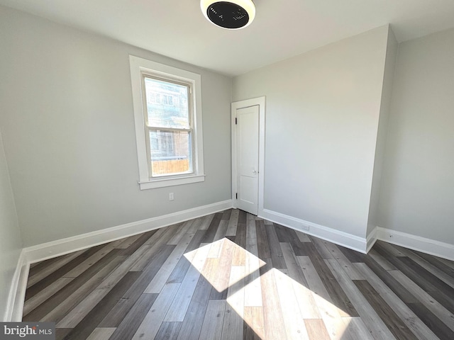 unfurnished room with dark wood-type flooring and baseboards