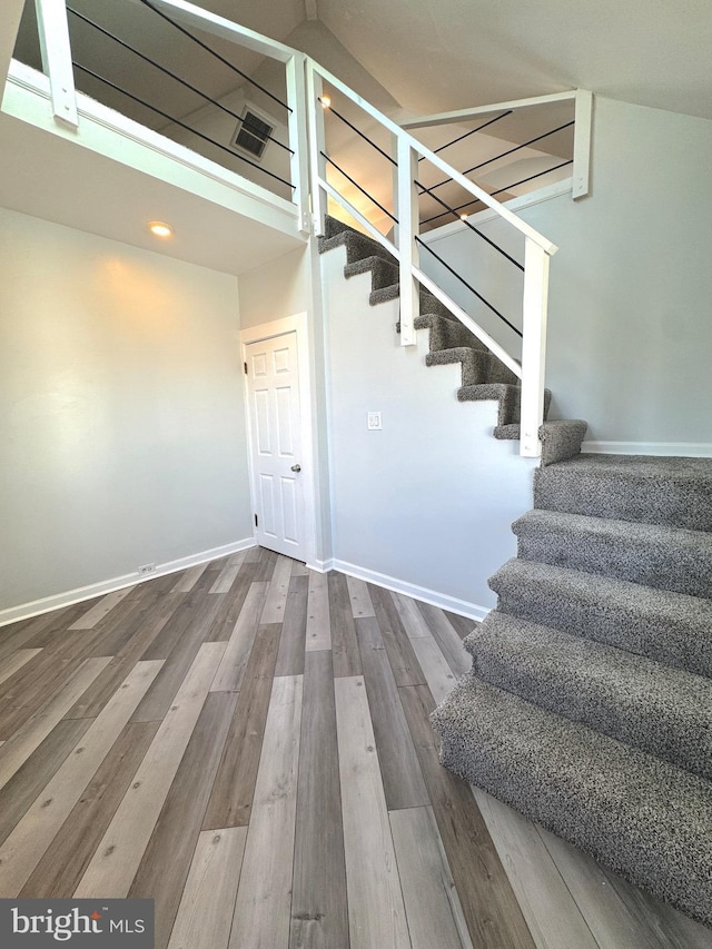 stairs with baseboards, visible vents, and wood finished floors