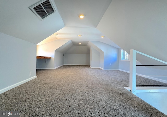 additional living space featuring carpet floors, baseboards, visible vents, and vaulted ceiling