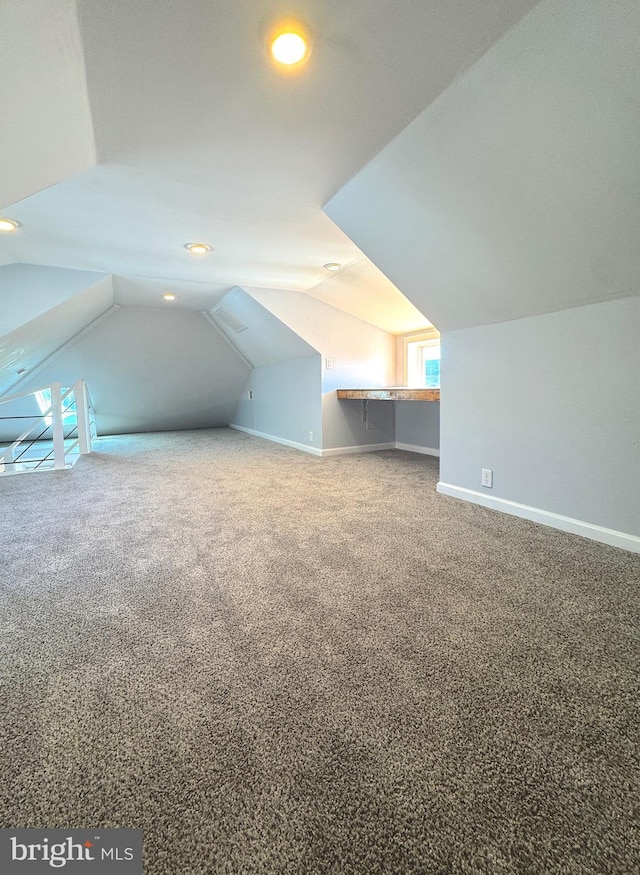 bonus room featuring lofted ceiling, carpet flooring, and baseboards