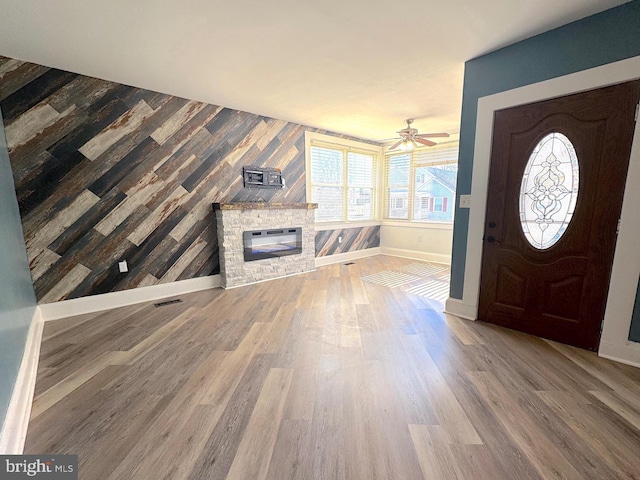 entryway featuring a stone fireplace, baseboards, and wood finished floors