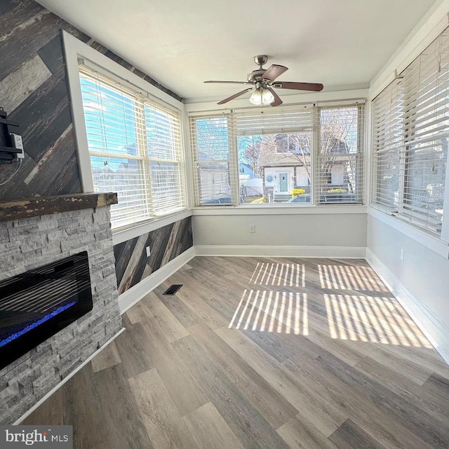 unfurnished sunroom featuring a fireplace, visible vents, and a ceiling fan