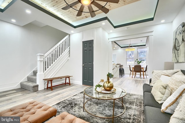 living room with light wood-type flooring, a tray ceiling, ceiling fan, and wood ceiling