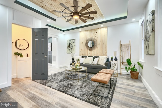 living room with light hardwood / wood-style floors, wood ceiling, and a tray ceiling