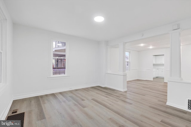 unfurnished room featuring decorative columns and light hardwood / wood-style flooring