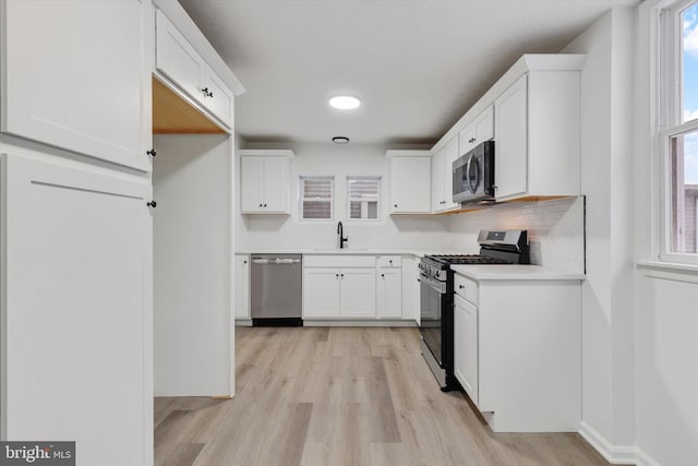 kitchen with white cabinets, appliances with stainless steel finishes, a healthy amount of sunlight, and sink