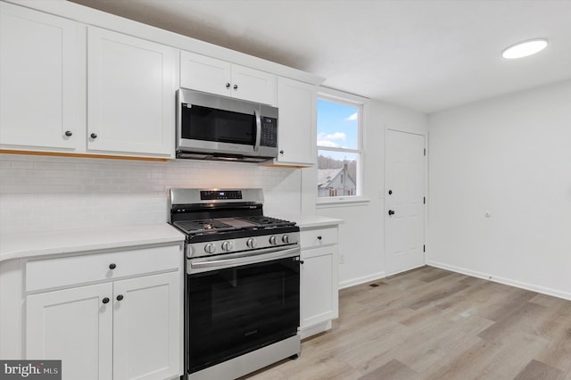 kitchen with decorative backsplash, light wood-type flooring, white cabinetry, and stainless steel appliances