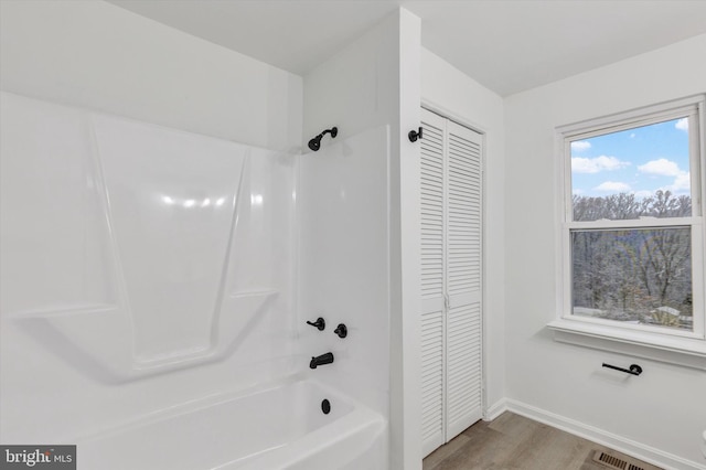 bathroom with wood-type flooring and bathing tub / shower combination