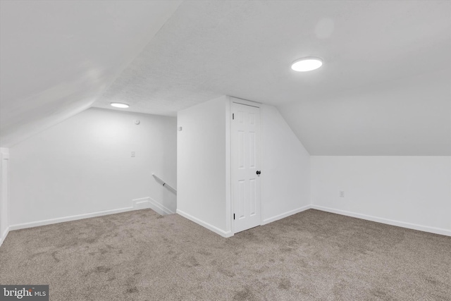 additional living space with carpet, a textured ceiling, and vaulted ceiling