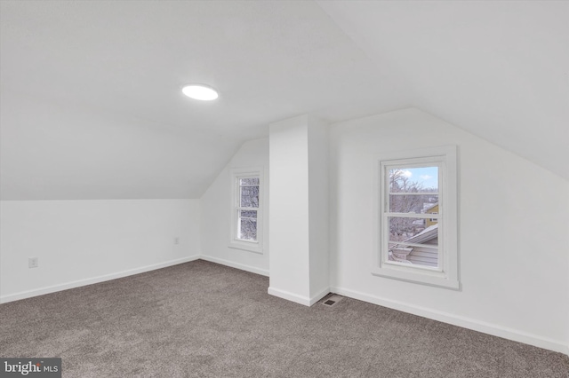 bonus room with dark colored carpet and lofted ceiling