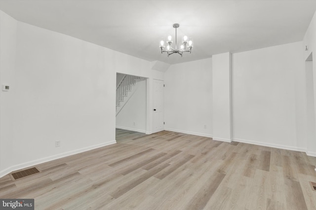 interior space featuring vaulted ceiling, light wood-type flooring, and a chandelier