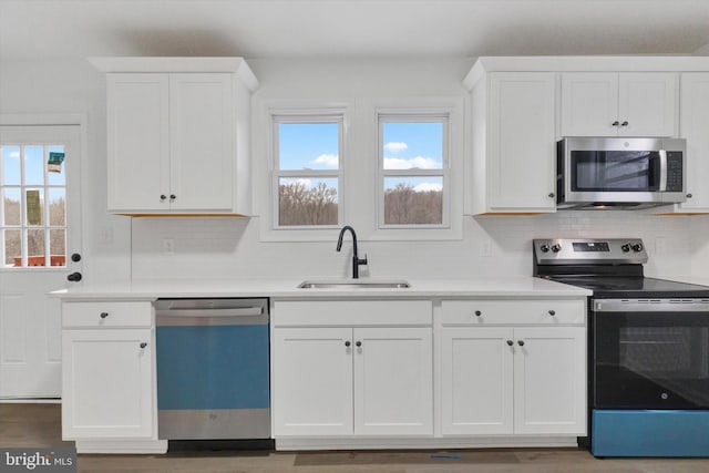 kitchen with tasteful backsplash, sink, white cabinets, and appliances with stainless steel finishes