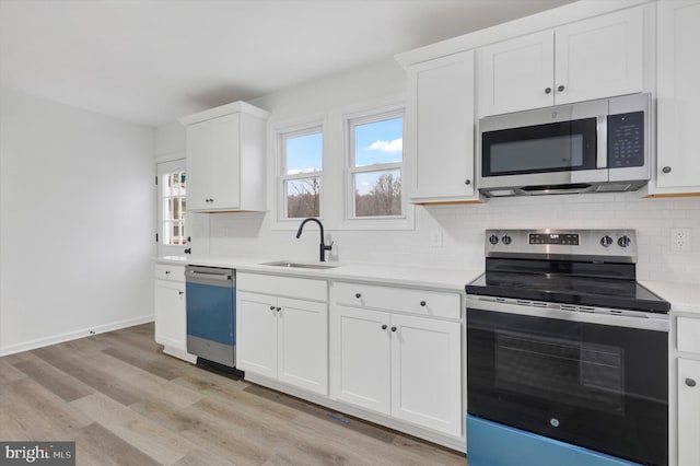 kitchen featuring white cabinets, sink, light hardwood / wood-style flooring, decorative backsplash, and stainless steel appliances