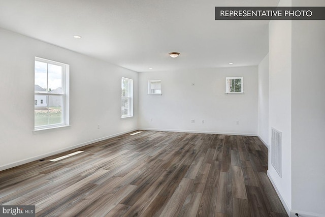 empty room featuring dark wood-type flooring and a wealth of natural light