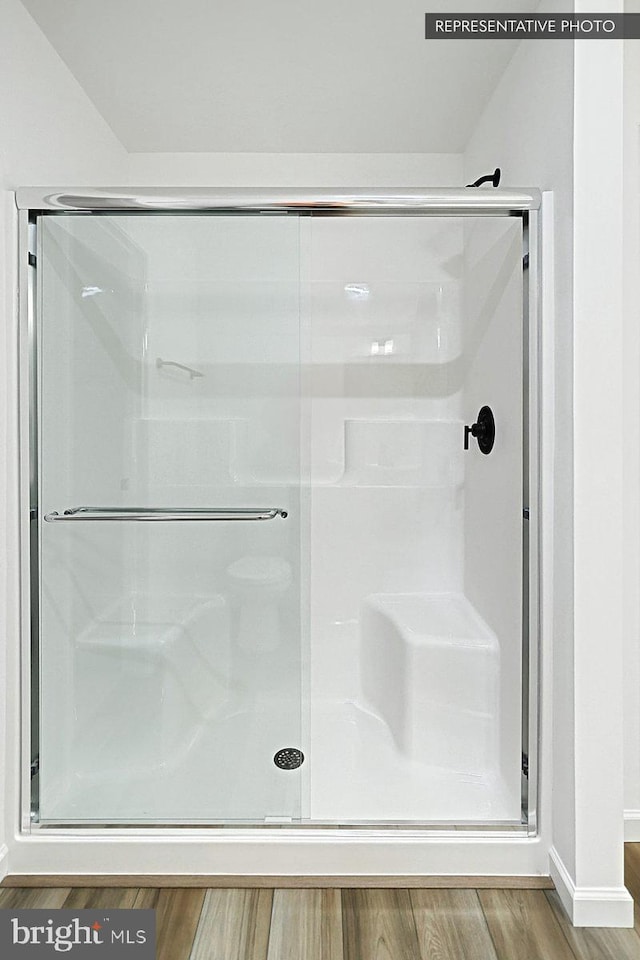 bathroom with wood-type flooring and an enclosed shower