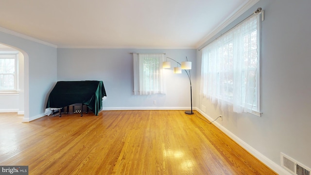 empty room with crown molding and light wood-type flooring