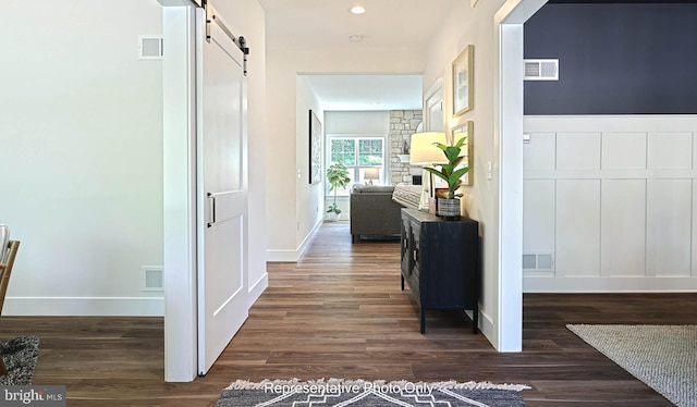 hallway with a barn door and dark hardwood / wood-style flooring