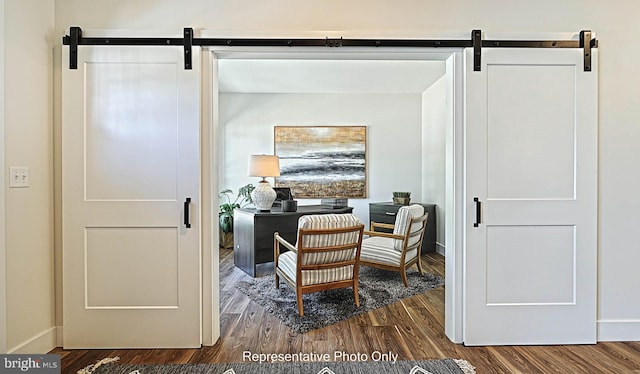 sitting room with hardwood / wood-style floors and a barn door