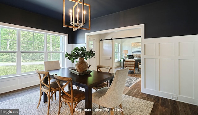 dining area featuring a chandelier, a barn door, and dark hardwood / wood-style floors