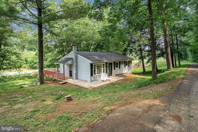 view of front of home with a deck and a front lawn