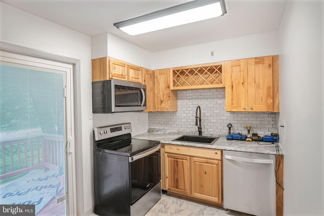 kitchen featuring decorative backsplash, stainless steel appliances, light stone countertops, and sink