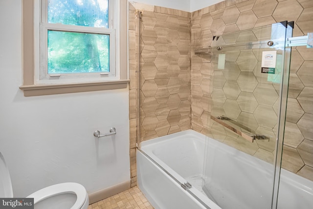 bathroom featuring toilet and combined bath / shower with glass door