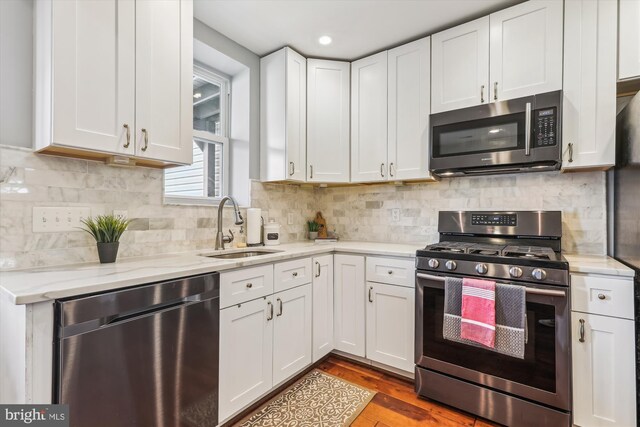 931 Farragut St NW, Washington, DC 20011 - kitchen with wood finished floors, white cabinetry, light stone counters, a sink, and appliances with stainless steel finishes