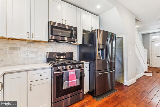 931 Farragut St NW, Washington, DC 20011 - kitchen featuring dark wood-style flooring, appliances with stainless steel finishes, white cabinetry, and tasteful backsplash