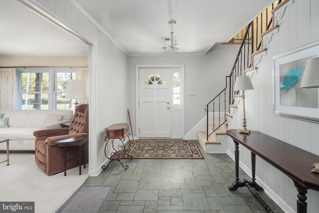 entryway featuring an inviting chandelier, ornamental molding, and a wealth of natural light