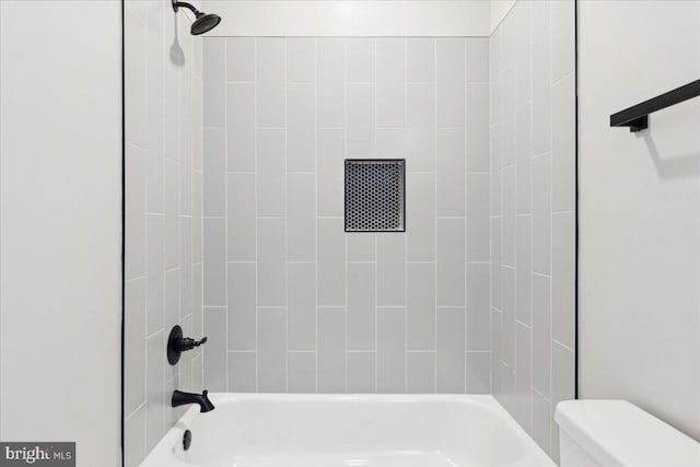 bathroom featuring tiled shower / bath combo and toilet