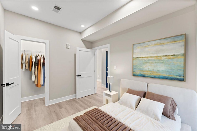 bedroom featuring a closet, a spacious closet, and light hardwood / wood-style flooring