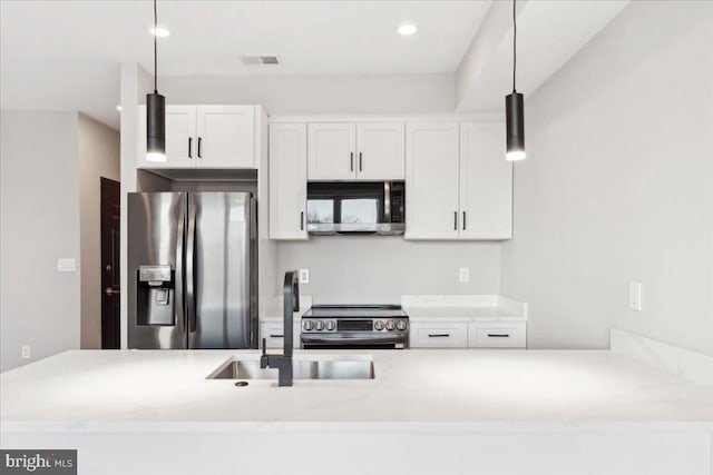 kitchen with pendant lighting, appliances with stainless steel finishes, and white cabinets