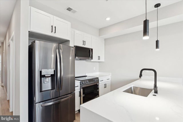 kitchen with appliances with stainless steel finishes, sink, white cabinets, hanging light fixtures, and light stone countertops