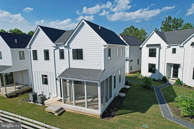 back of property featuring cooling unit, a sunroom, and a lawn