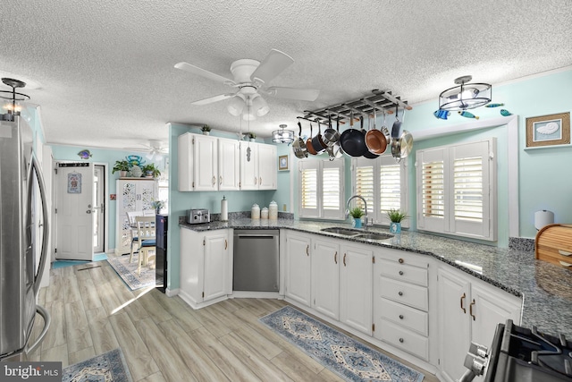 kitchen featuring dark stone counters, sink, white cabinets, and stainless steel appliances