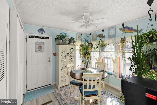 dining space featuring ceiling fan, light hardwood / wood-style flooring, crown molding, and a textured ceiling