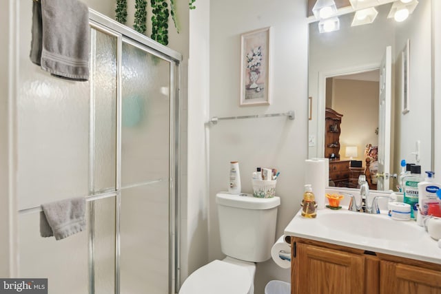 bathroom featuring vanity, toilet, and a shower with door