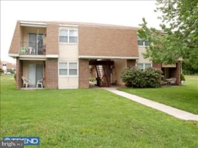 rear view of house featuring a lawn and a balcony