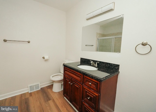 bathroom featuring hardwood / wood-style floors, vanity, toilet, and walk in shower