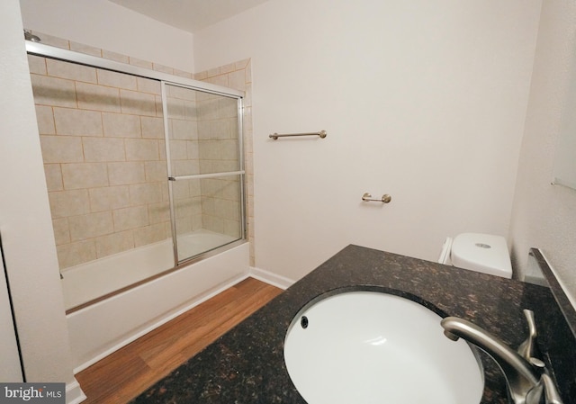 full bathroom with enclosed tub / shower combo, toilet, wood-type flooring, and sink