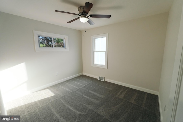 spare room featuring dark carpet and ceiling fan