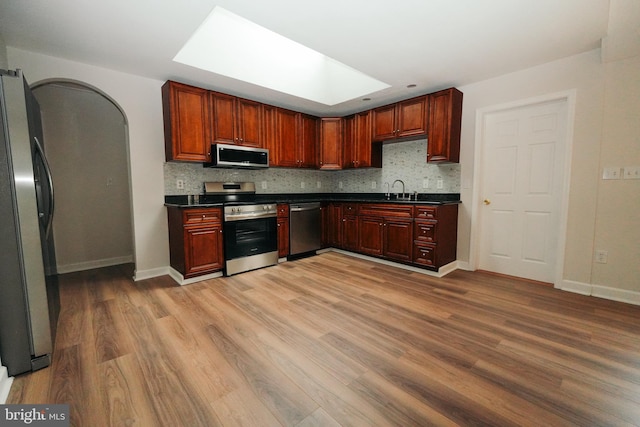 kitchen featuring tasteful backsplash, a skylight, sink, and appliances with stainless steel finishes