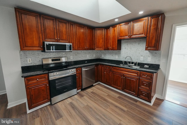 kitchen featuring dark stone countertops, sink, stainless steel appliances, and wood-type flooring