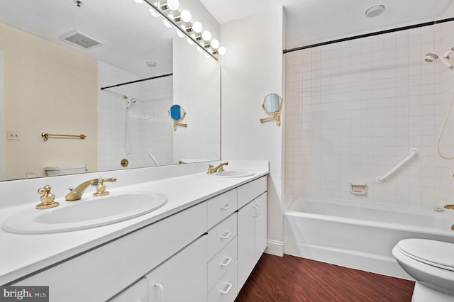 full bathroom with vanity, tiled shower / bath combo, hardwood / wood-style flooring, and toilet