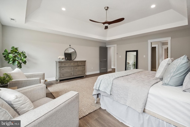 bedroom featuring ceiling fan, dark hardwood / wood-style floors, and a tray ceiling