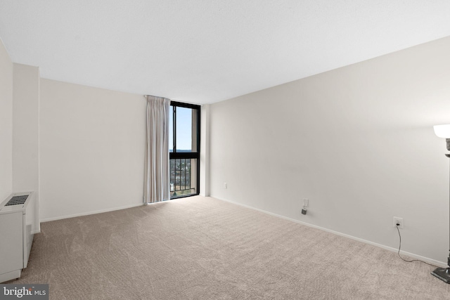 unfurnished room featuring light carpet and floor to ceiling windows