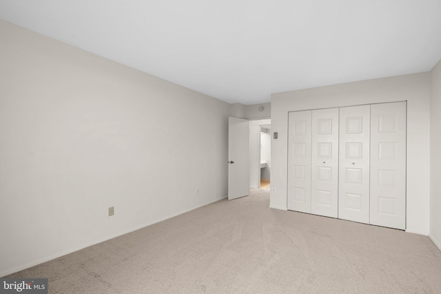 unfurnished bedroom with light carpet and a closet