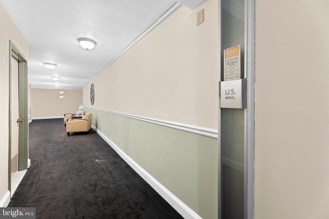 corridor featuring a textured ceiling and dark colored carpet